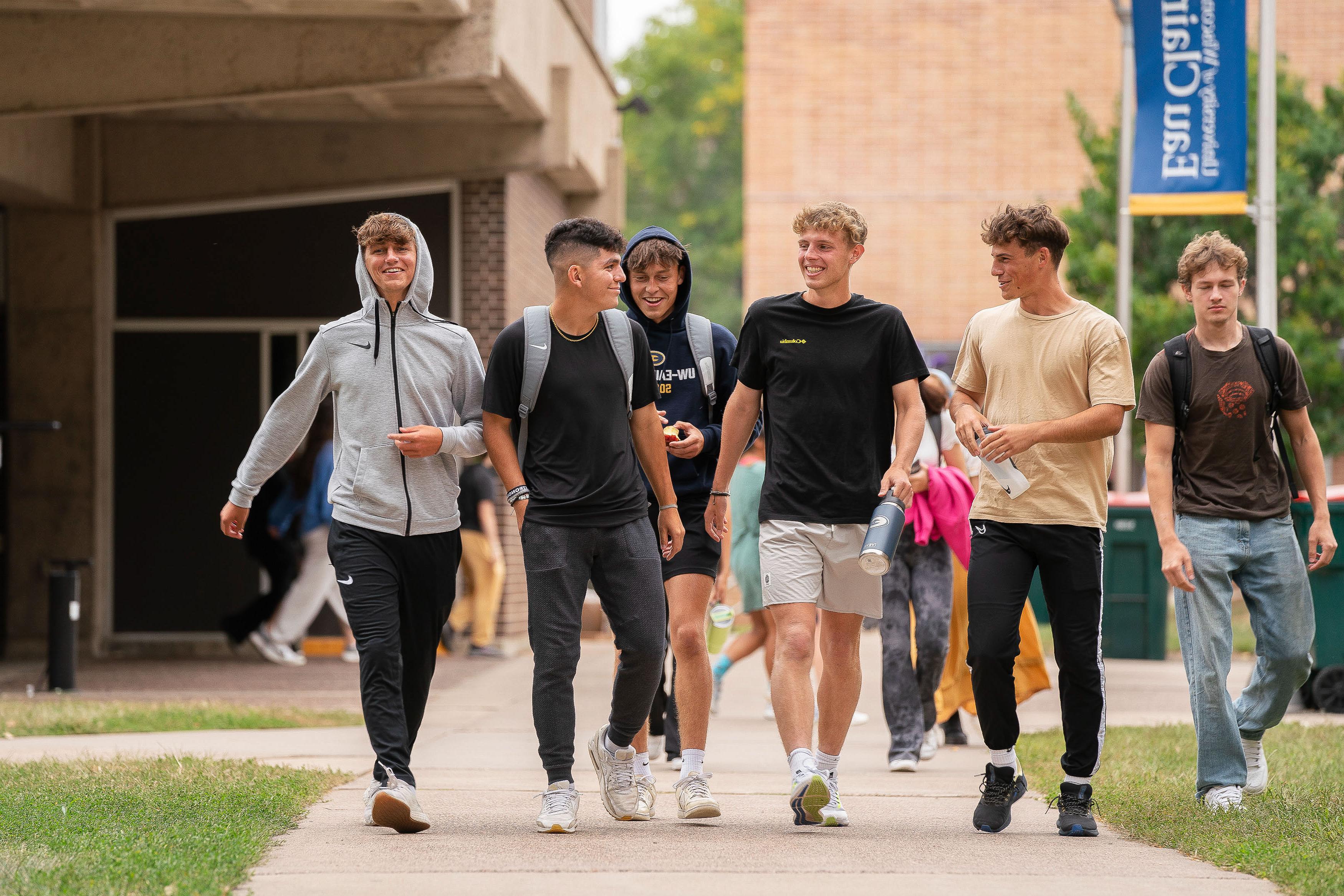 Students laughing and walking on 的 sidewalk on upper campus.