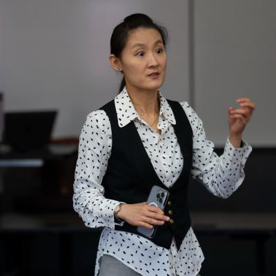 faculty standing in front of a class, using hand gestures 